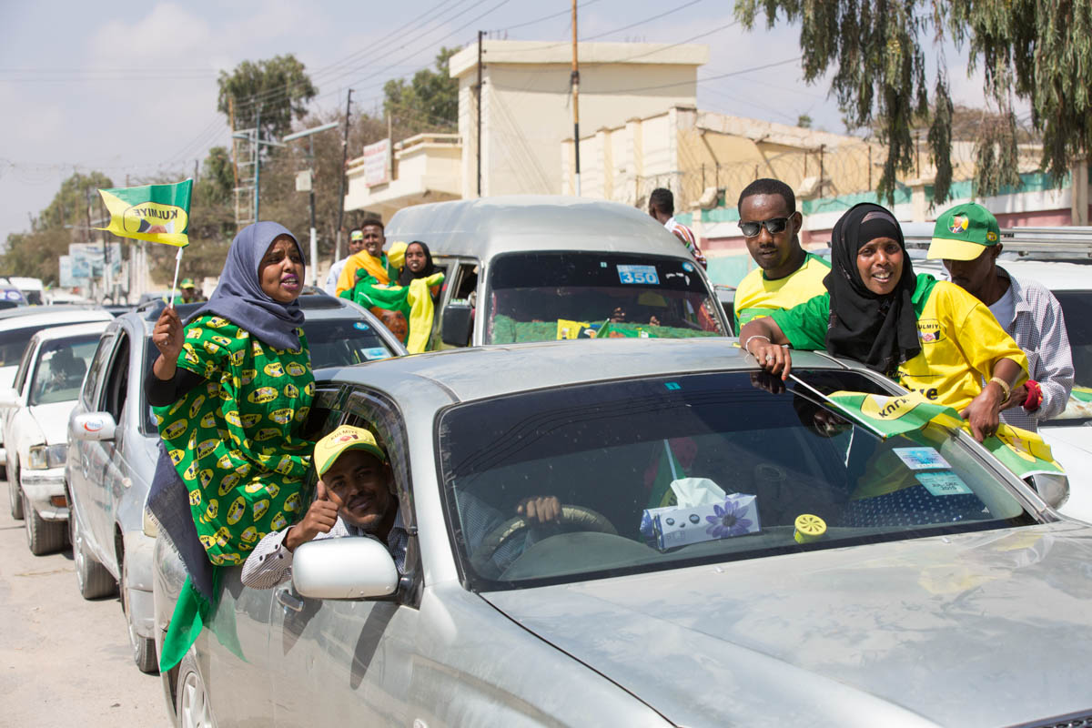 Supporters of Kulmiye (Peace, Unity and Development Party), the current ruling party, drive through the streets of Hargeisa displaying party colours and blaring party-promoting music, on their way to a rally. Each day only one designated party can campaign, a rule created to avoid potential conflict and security issues. [Kate Stanworth/Saferworld/Al Jazeera]