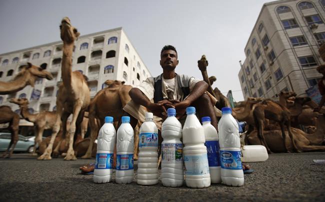 Man sitting on street with bottles of milk in front of him