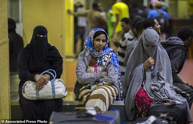 In this photo taken Friday, Dec. 22, 2017, Ethiopian women sit on a luggage conveyor belt as they wait for family members after being deported from Saudi Arabia, at the airport in Addis Ababa, Ethiopia. Undocumented Ethiopian migrants who are being forcibly deported from Saudi Arabia by the thousands in a new crackdown say they were mistreated by authorities while detained. (AP Photo/Mulugeta Ayene)