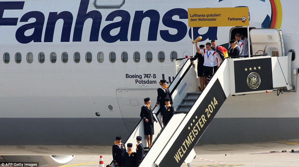 We're back! Philipp Lahm leads out his team of the private Boeing 747, with the steps decorated with a message 'World Cup winners 2014' and four stars