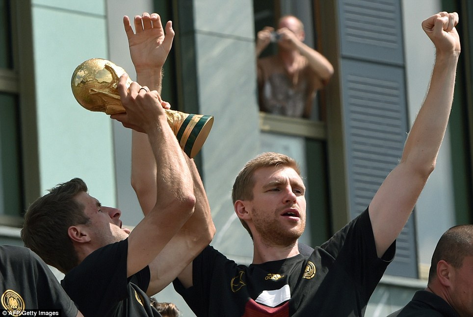 Nice picture! A man hangs out of a widow to capture Muller lift the trophy alongside Mertesacker