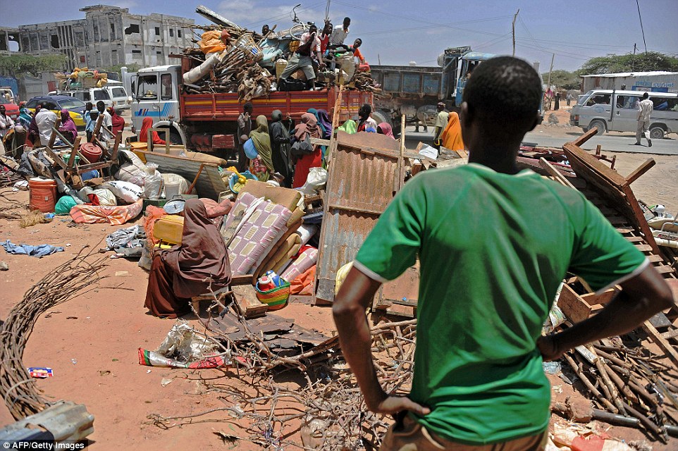 A boy watches as Somali refugees load their belongings onto a truck - knowing that the hard life they all led just got even harder