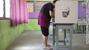 A voter wearing shorts and flip-flops fills out a ballot at a polling station in the Desa Petaling area of Kuala Lumpur, Malaysia, on Wednesday. Some voters were turned away by officials citing dress restrictions -- despite assurances that would not happen.