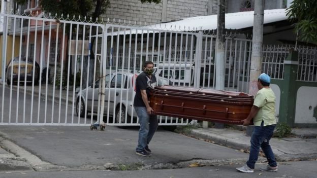 Two men carry a coffin on the streets of Guayaquil, Ecuador