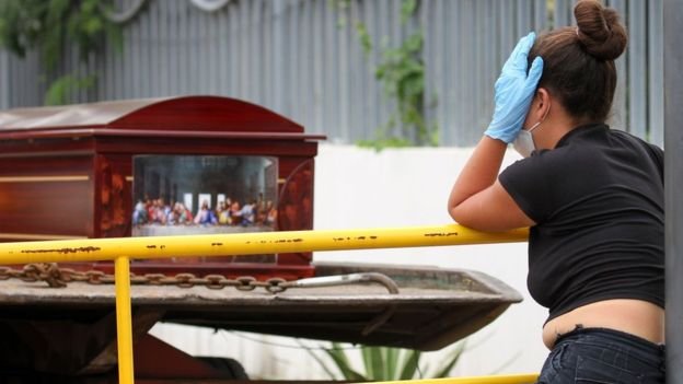 A woman stands by a coffin in Guayaquil, Ecuador