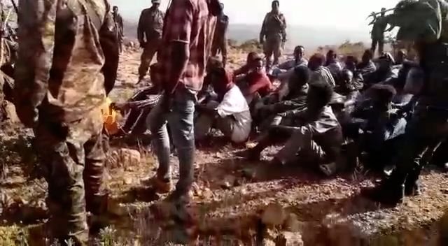 Qofka dharka shacabka xiran oo dhulka fadhiya ayaa la arkayaa waxyar ka hor inta ay ciidamadu toogasha ku dilin