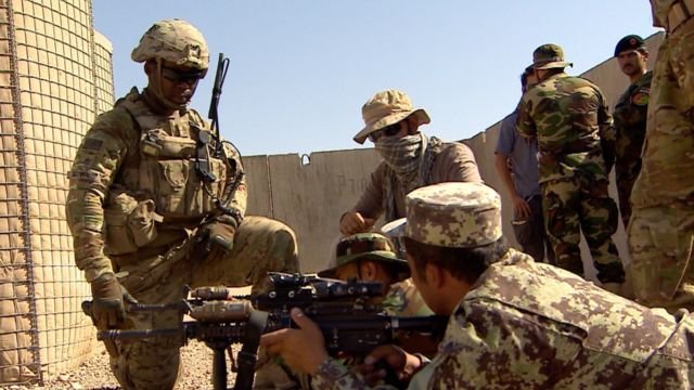 US troops training the Afghan Army 215th Corp in Helmand, Afghanistan, July 2016 - US soldier kneels beside Afghan soldiers lying on the ground with rifles