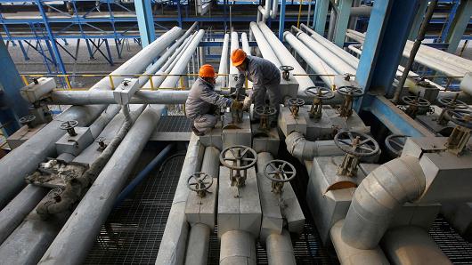 Employees close a valve of a pipe at a PetroChina refinery in Lanzhou, Gansu province.