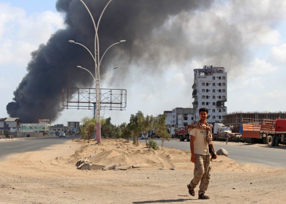 A fighter from the separatist Southern Transitional Council walks with smoke billowing in the background in the government's de facto capital Aden, as they move closer to taking full control of the southern city on Tuesday.